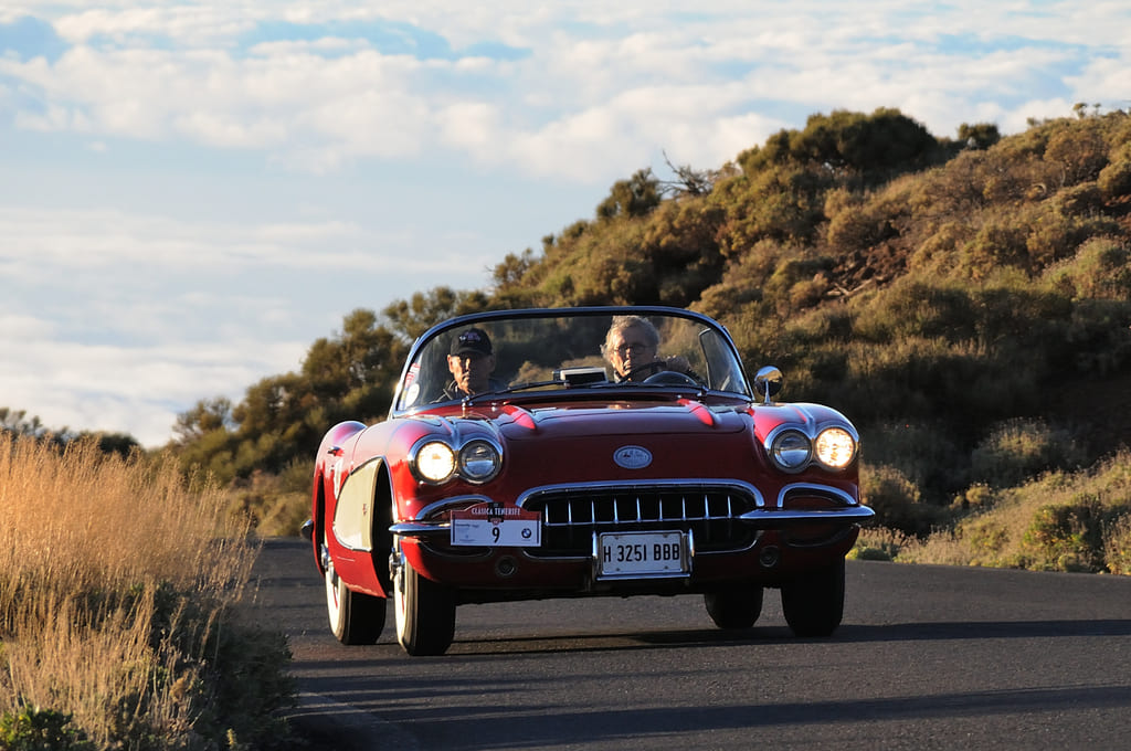 foto de un chevrolet corvette de los 50 rojo, por carretera en un atardecer